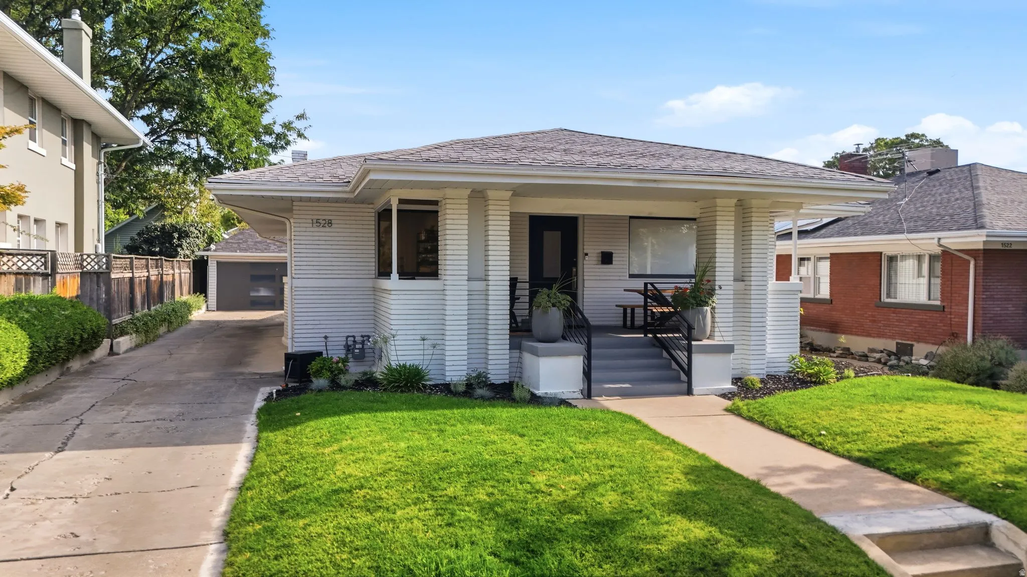 Craftsman bungalow with a covered front porch, perfectly manicured lawn, long driveway, and detached 2-car garage