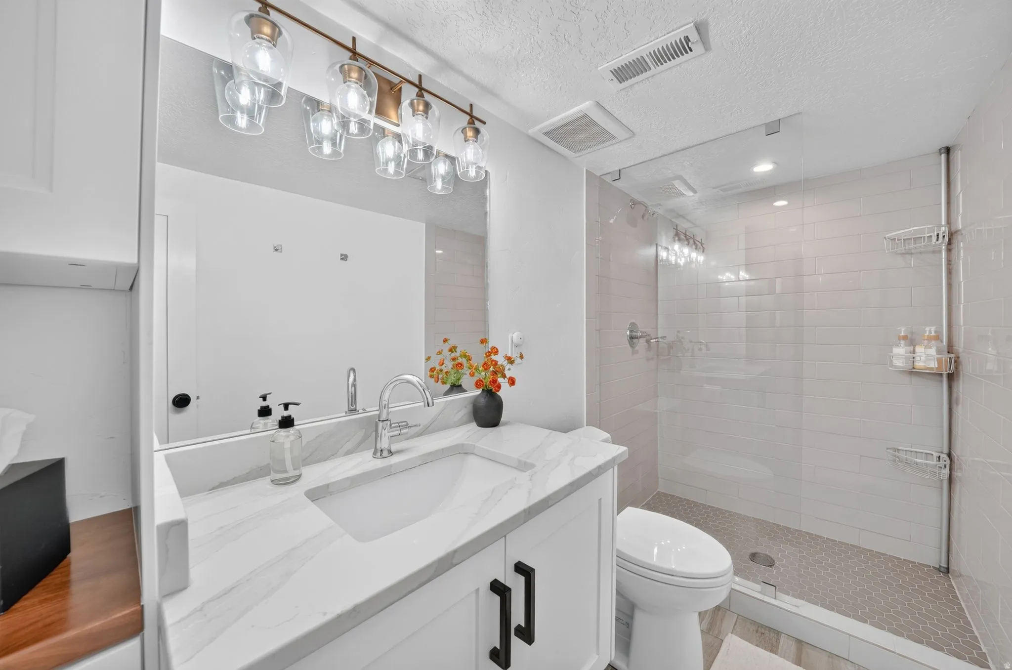 3/4 bathroom in basement,  quartz countertops, linen cabinet, spa tile shower with euro glass and hexagon mosaic floor.