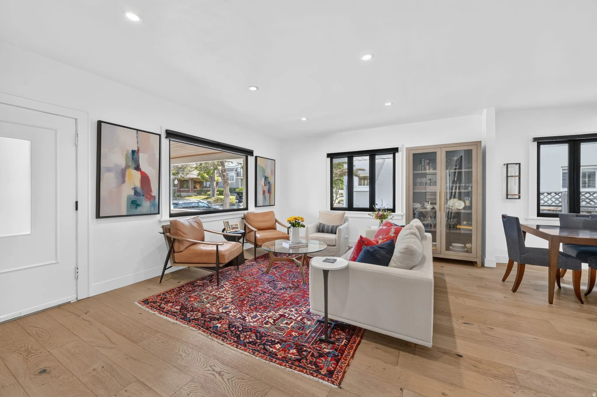 Open-concept living area, white oak hardwood flooring, recessed lighting, and expansive windows with black trim