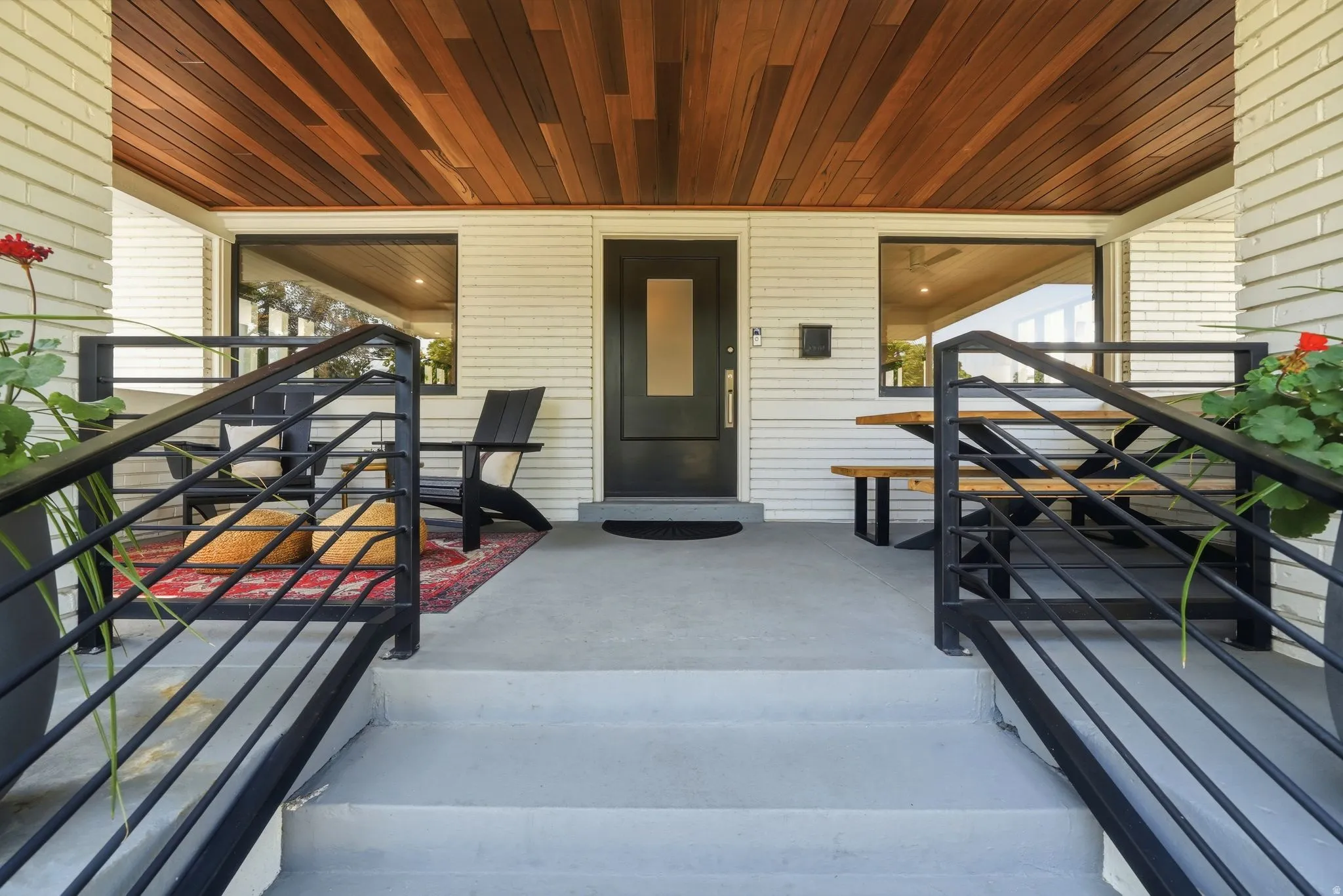 Covered front porch with brand-new Brazilian walnut ceiling, black metal railings, spacious seating area, & timeless Craftsman charm