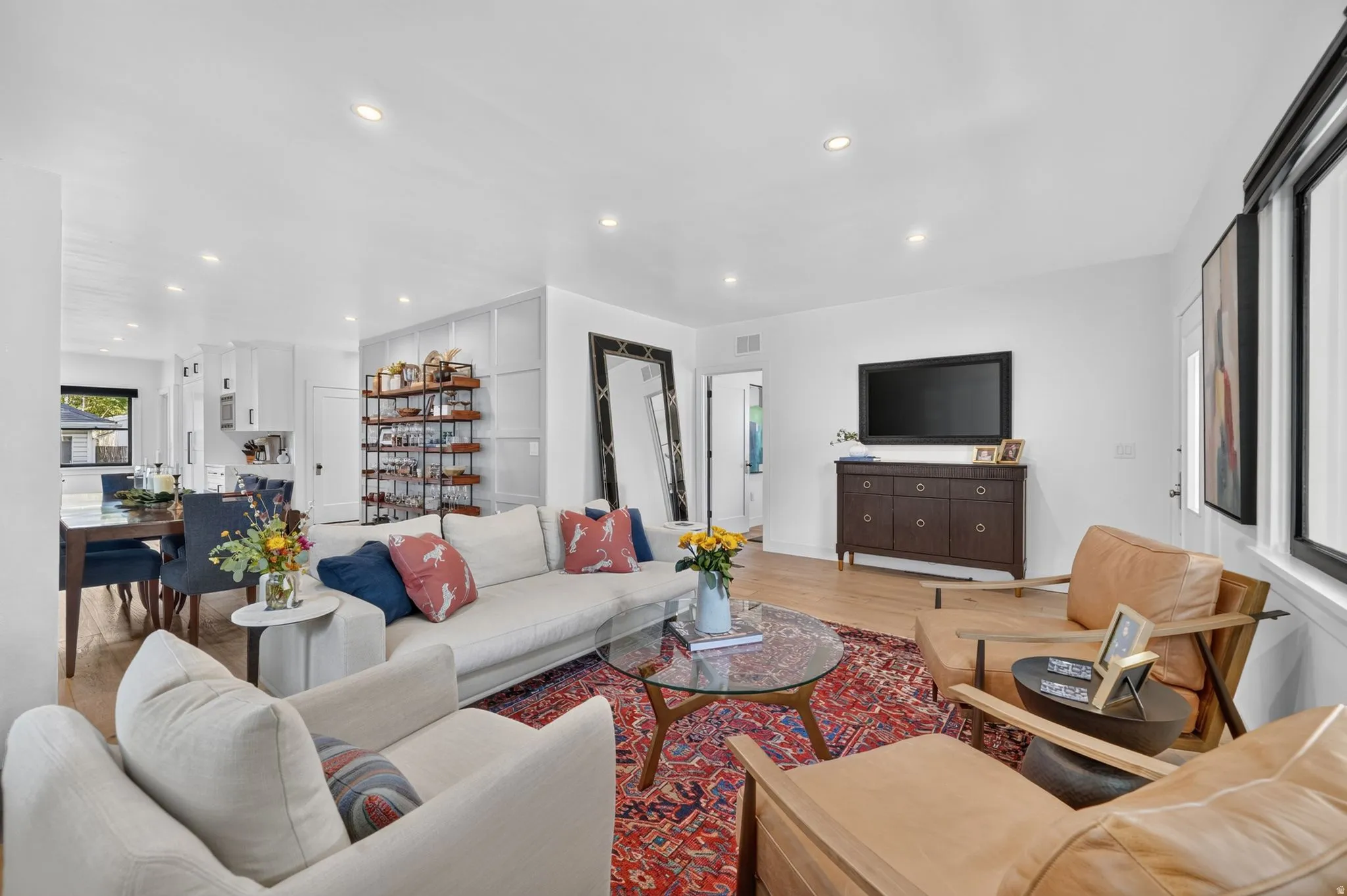 Open-concept entry, living room, and dining area.  White oak hardwood flooring throughout, recessed lighting, and ample natural light coming through expansive windows.