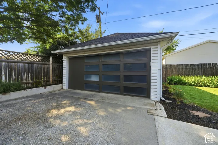 Detached garage horizontal frosted glass panels.  EV car charger on side of house near garage.