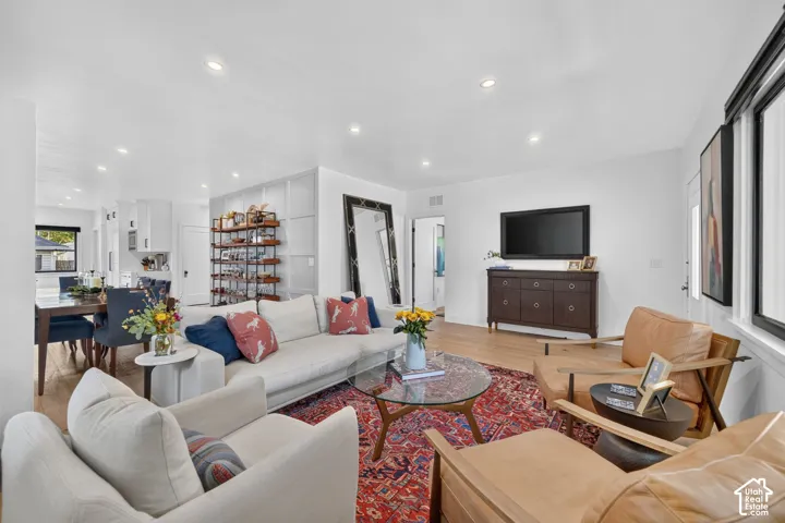 Open-concept entry, living room, and dining area.  White oak hardwood flooring throughout, recessed lighting, and ample natural light coming through expansive windows.