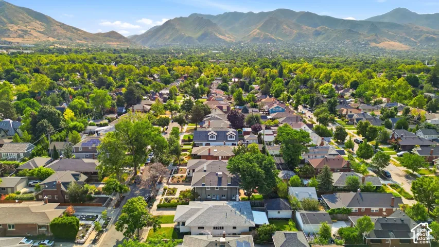 Expansive residential area featuring established homes, mature trees, and mountainous terrain in the background