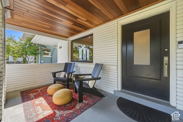 Covered front porch with brand-new Bolivian walnut ceiling, black metal railings, spacious seating area, & timeless Craftsman charm