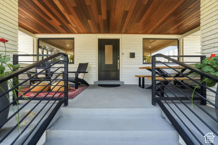 Covered front porch with brand-new Bolivian walnut ceiling, black metal railings, spacious seating area, & timeless Craftsman charm