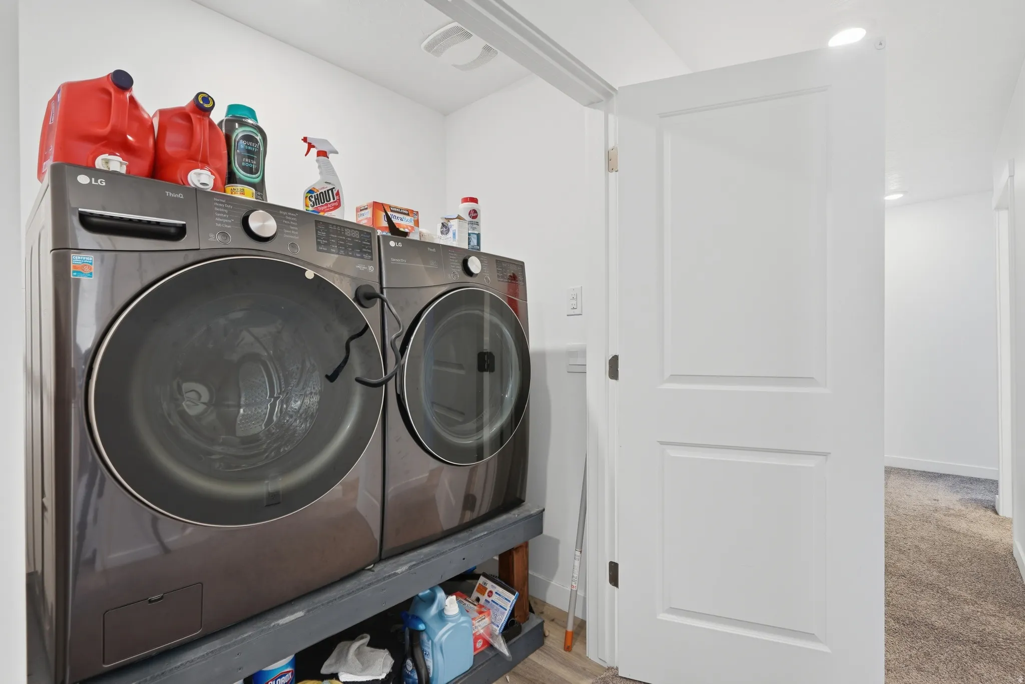 Dedicated laundry area featuring modern front-load appliances, recessed lighting, and white paneled door