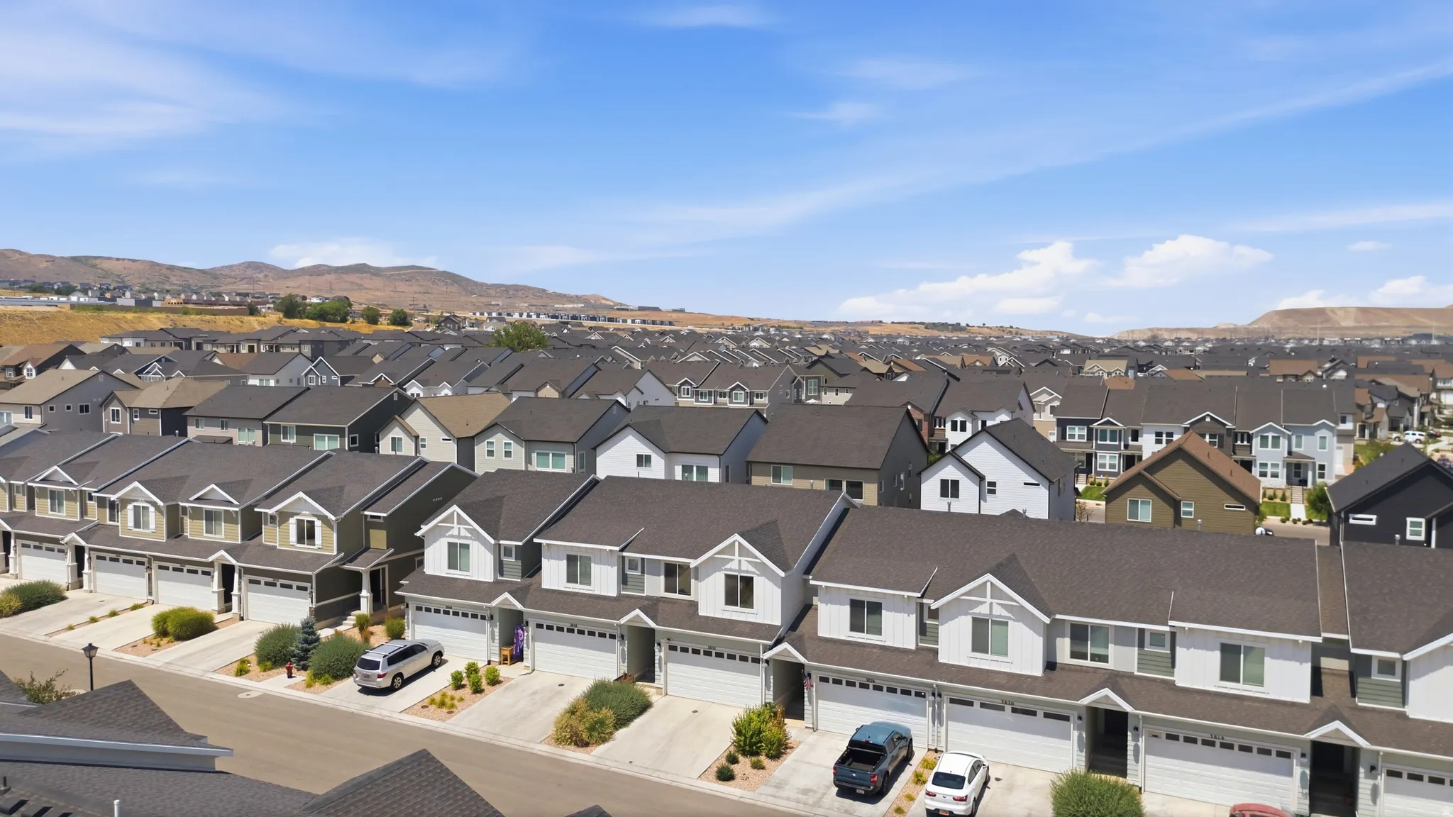 Residential neighborhood featuring contemporary homes with attached garages, dark shingle roofs, and light-toned siding