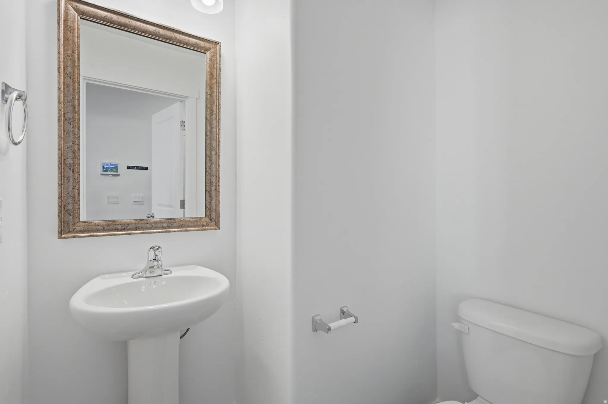 White pedestal sink with a single-handle faucet and a framed mirror