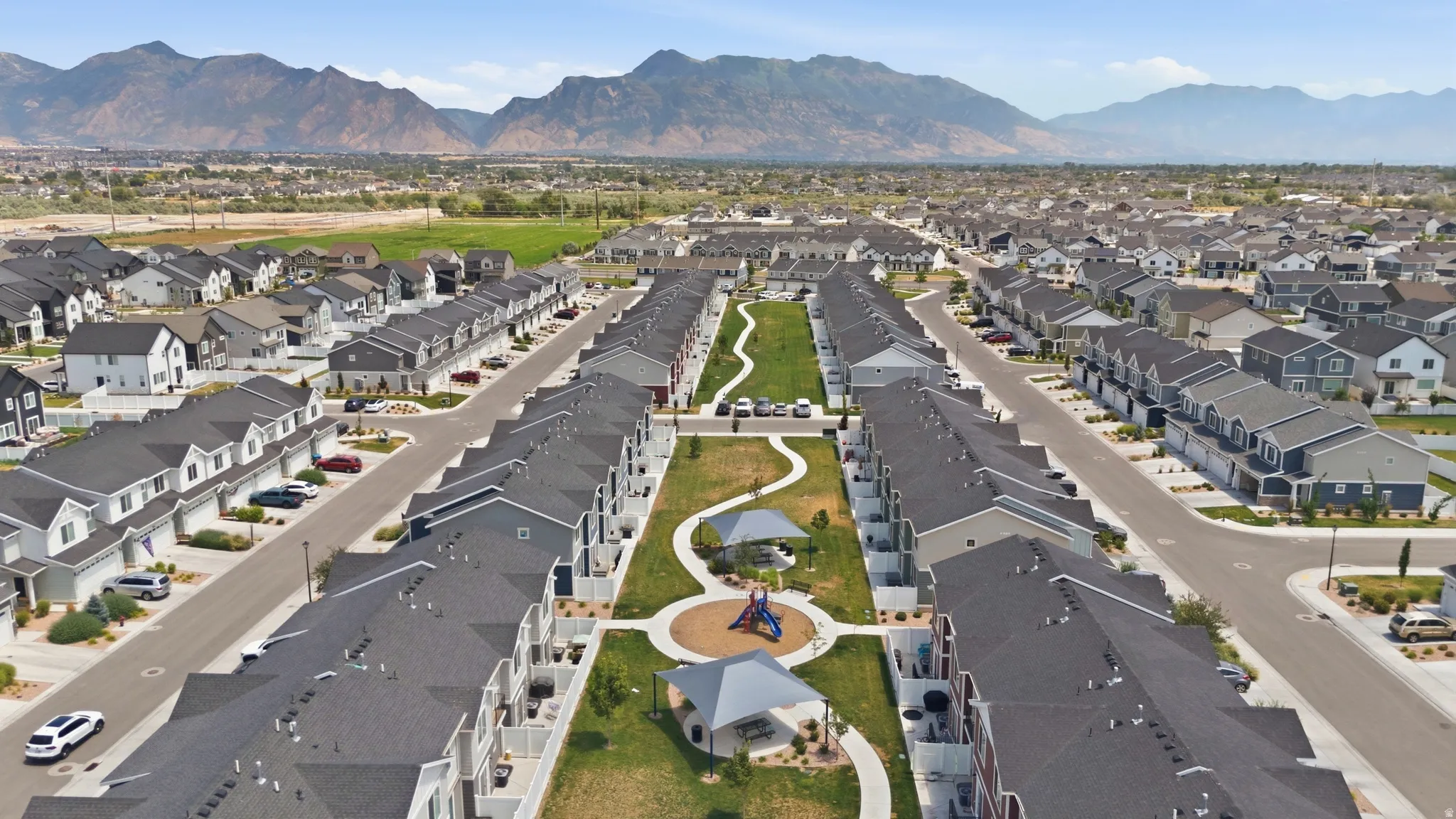 Community green space with walking paths, playground structures, and shade canopies