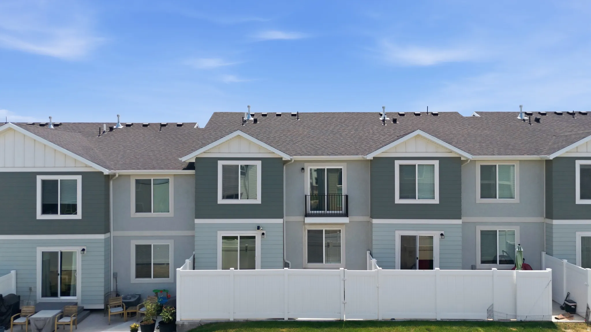Modern townhome exteriors featuring multi-toned siding, gabled rooflines, and private patios