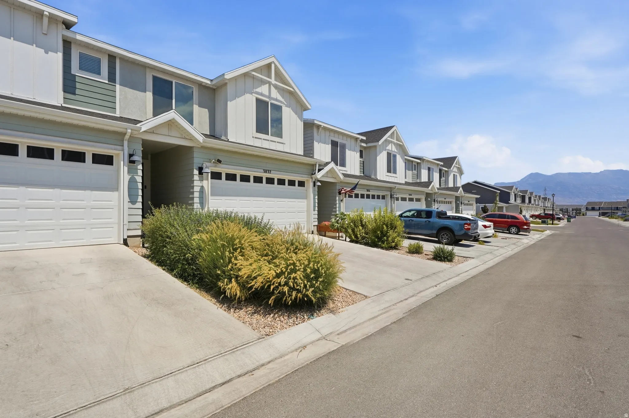 Contemporary townhome exterior with two-car garage, prominent gabled dormers, multi-pane windows, and a covered entry