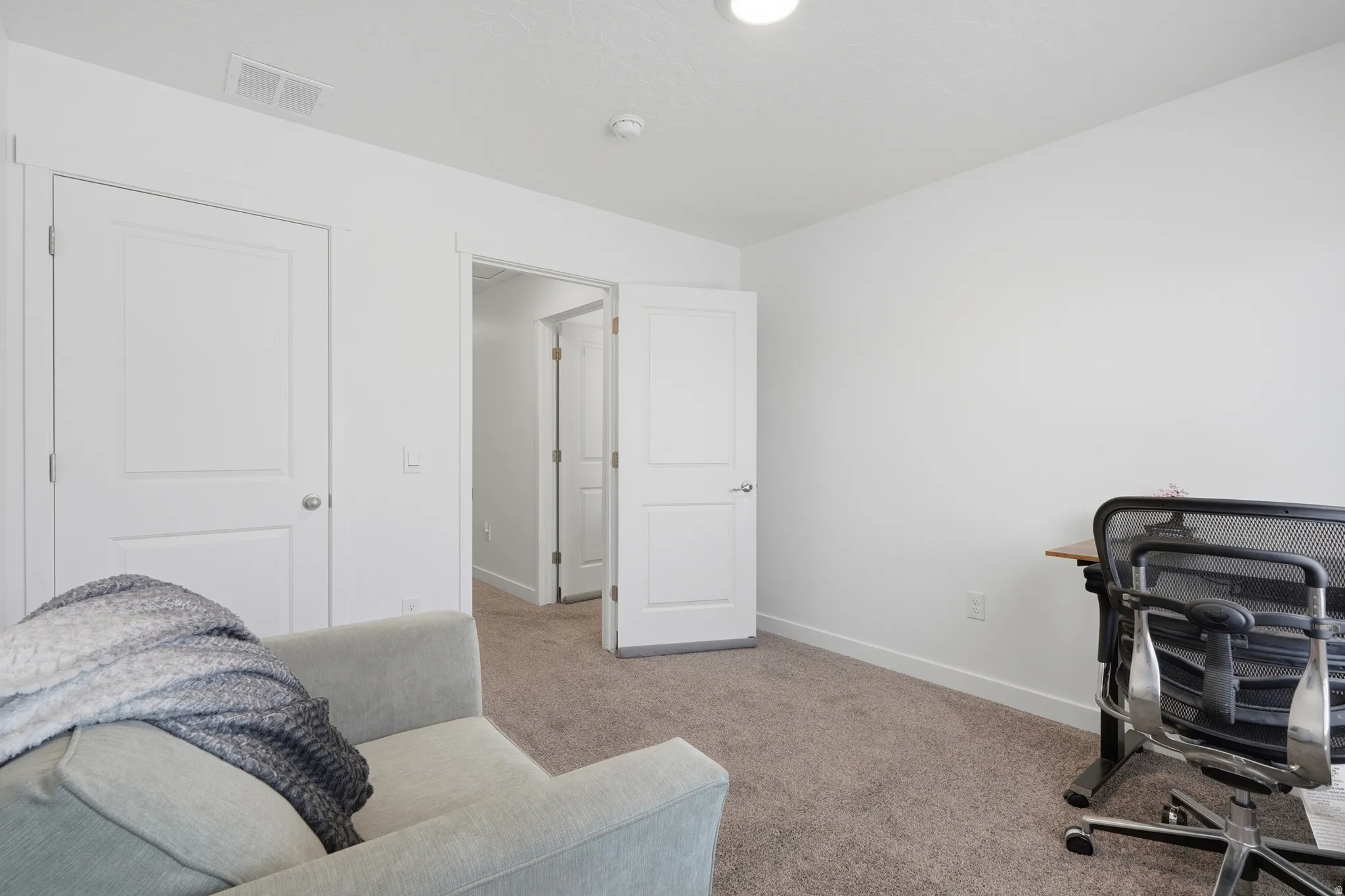 Spacious room featuring neutral carpet flooring, white walls, and bright overhead lighting