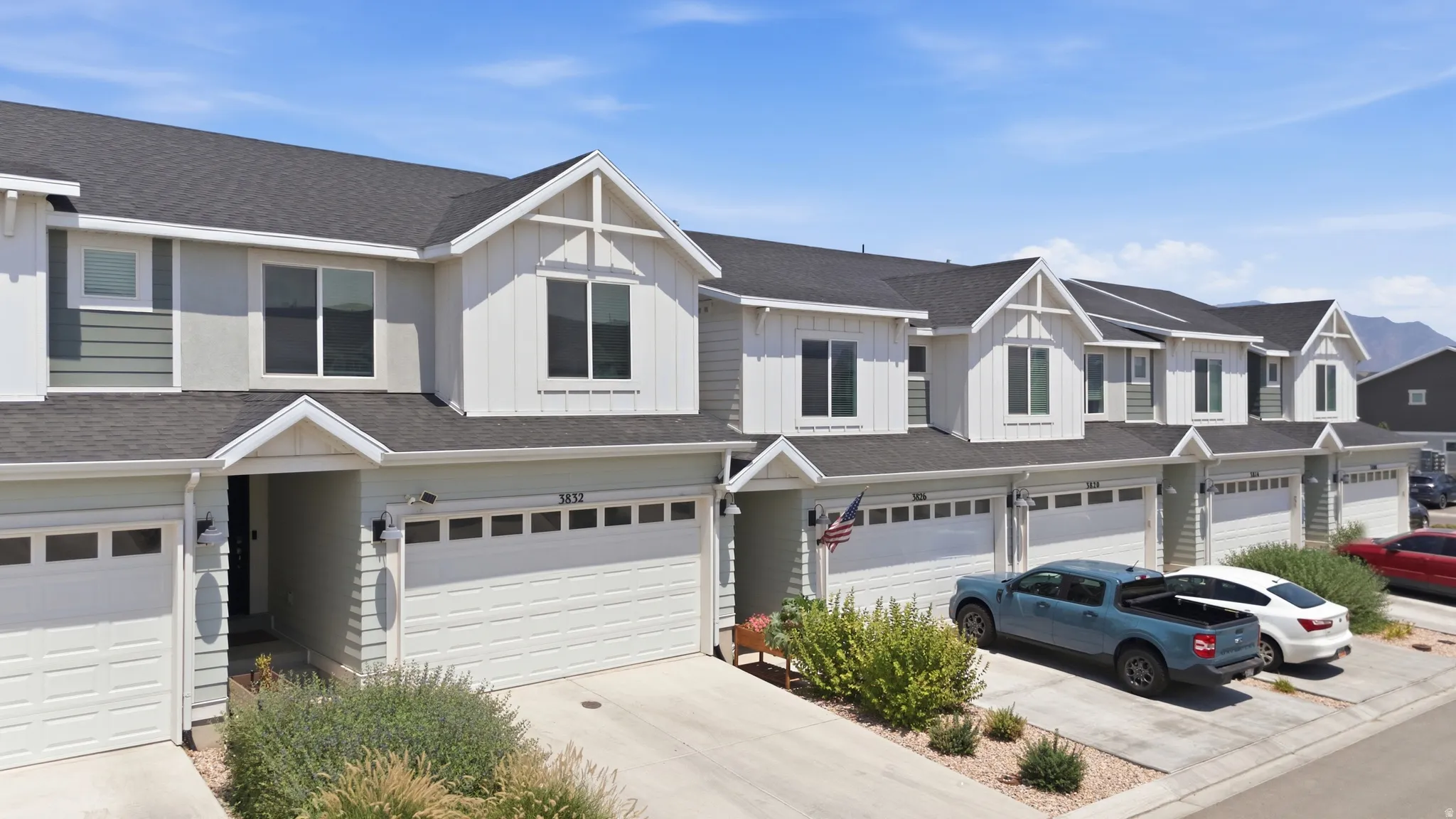 Contemporary townhome exterior with mixed material siding, prominent gabled dormers, and dark shingle roofing