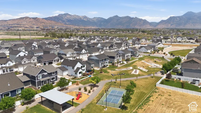 Residential development featuring a community park, covered picnic area, pickleball court, and playground equipment, all set against a prominent mountain backdrop