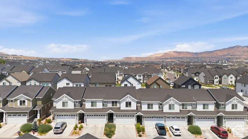 Residential street featuring two-story homes with attached garages, dark shingle roofs, and light-colored siding
