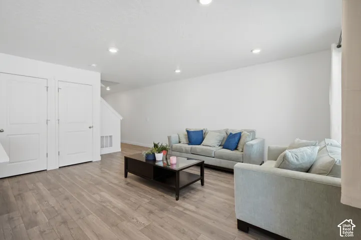 Spacious living area featuring wood-finish flooring, recessed lighting, white walls, and bright white interior doors