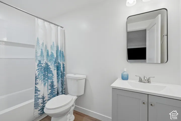 Bathroom featuring a white bathtub with subway tile surround, a toilet, and a vanity with gray cabinetry and a white countertop