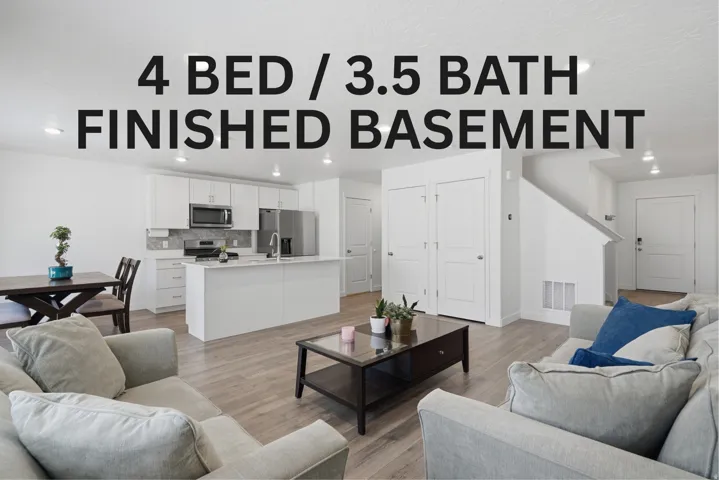 Open-concept living area featuring wood-finish flooring, a contemporary kitchen with white cabinetry, stainless steel appliances, a kitchen island, and recessed lighting