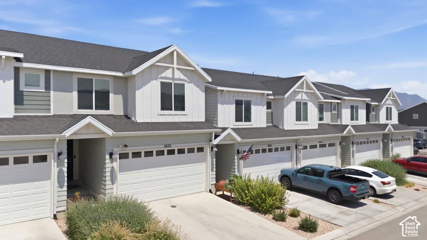 Contemporary townhome exterior with mixed material siding, prominent gabled dormers, and dark shingle roofing