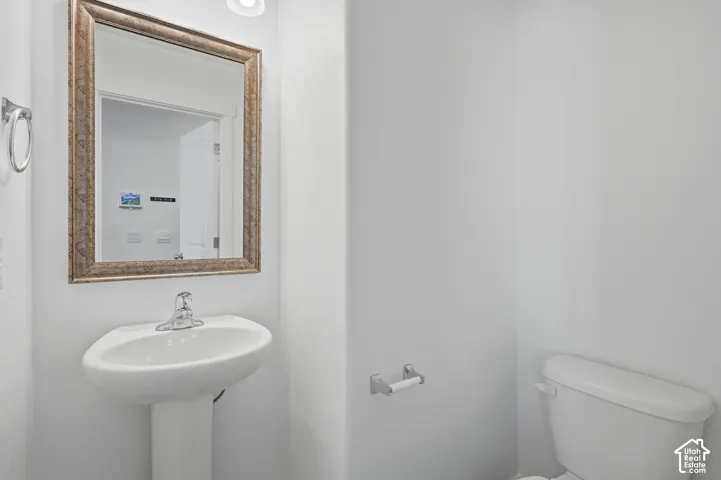 White pedestal sink with a single-handle faucet and a framed mirror