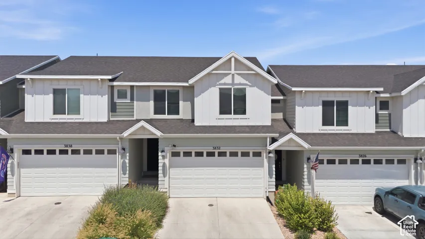 Contemporary townhome exterior featuring light-colored siding, dark shingle roofing, and integrated single-car garages