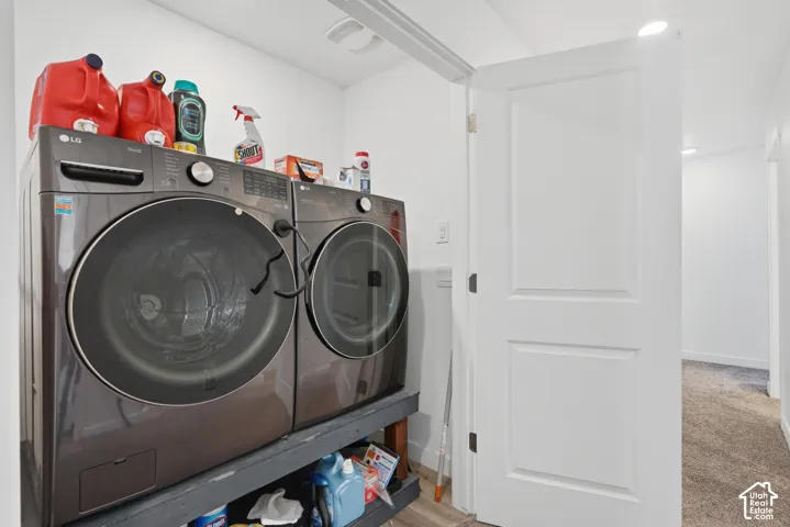 Dedicated laundry area featuring modern front-load appliances, recessed lighting, and white paneled door