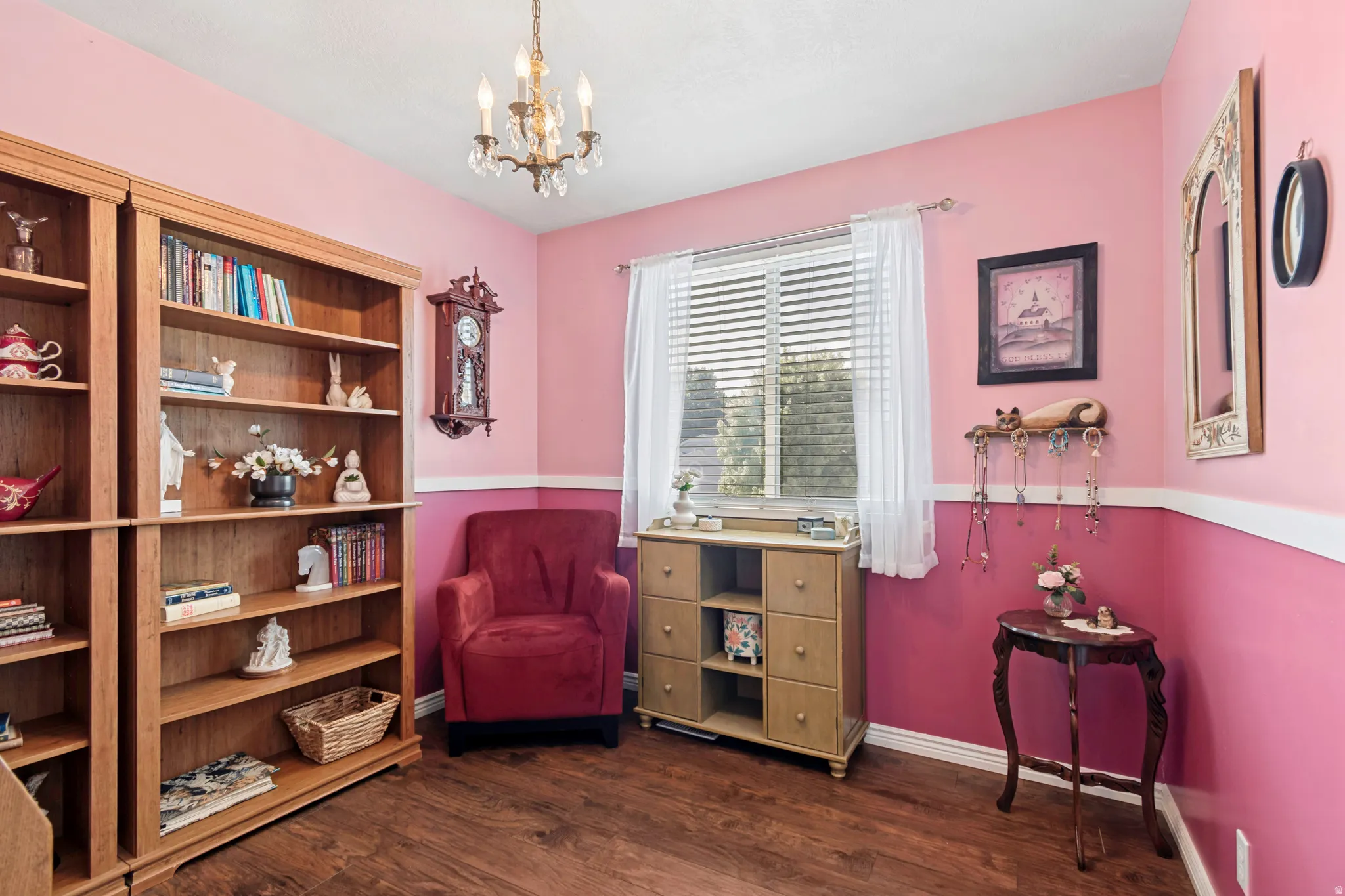 Room featuring wood-finish flooring, a decorative chandelier, and a large window with blinds