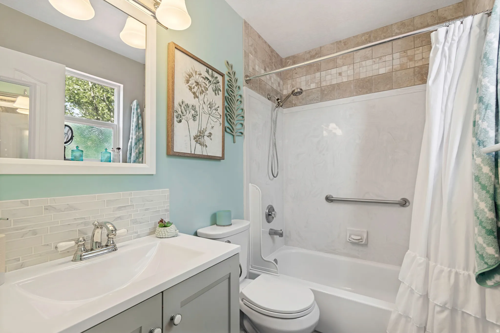 Bathroom featuring a white vanity with an integrated sink, a rectangular mirror, and a three-light fixture