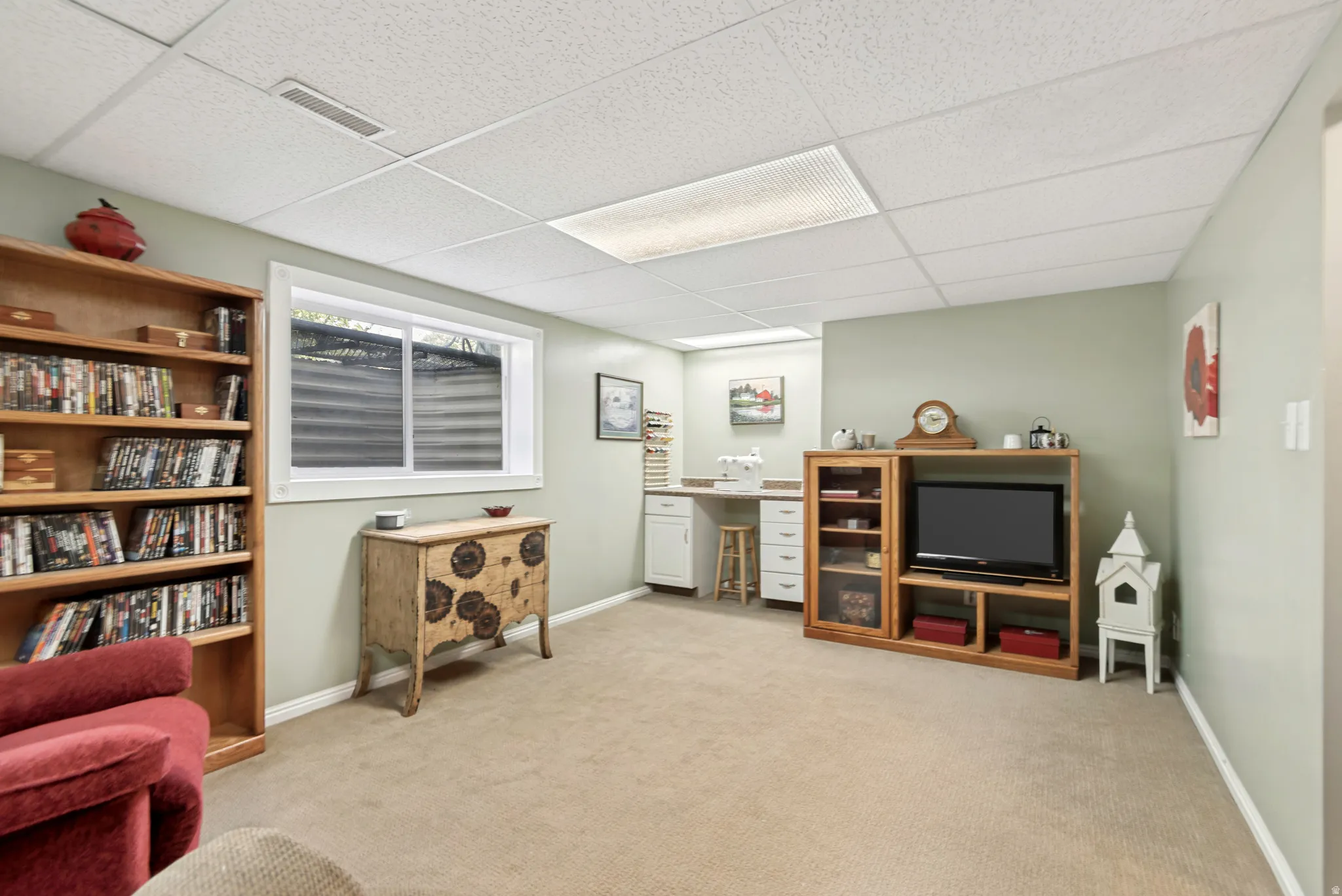 Finished lower-level space featuring soft green wall paint and light-colored carpeting