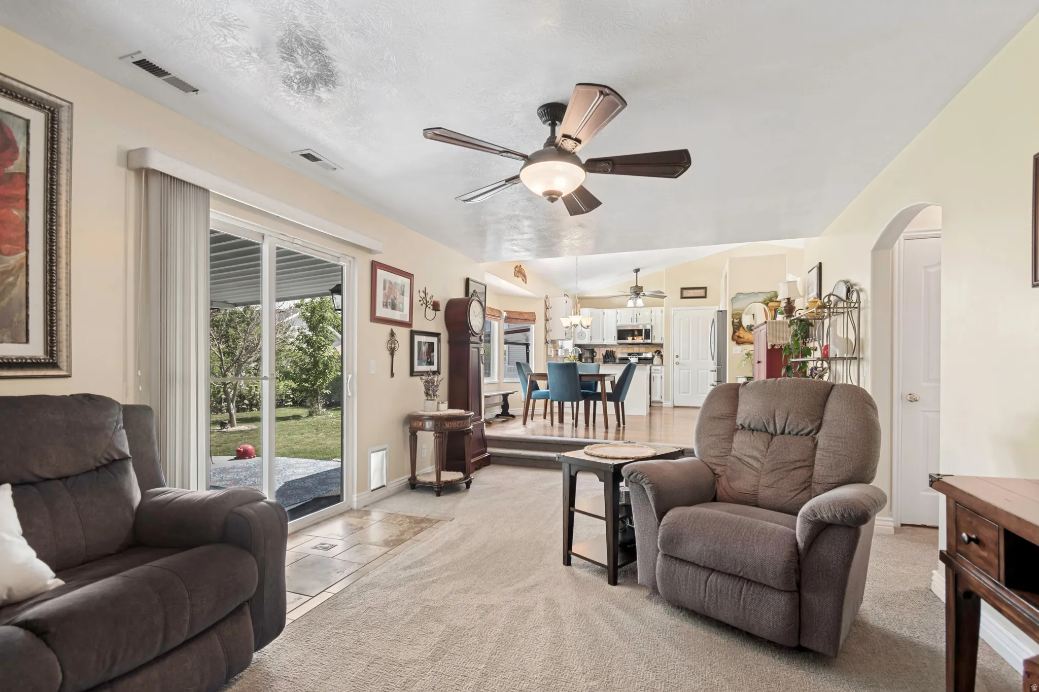 Living area featuring light-colored carpet flooring and a ceiling fan with integrated lighting