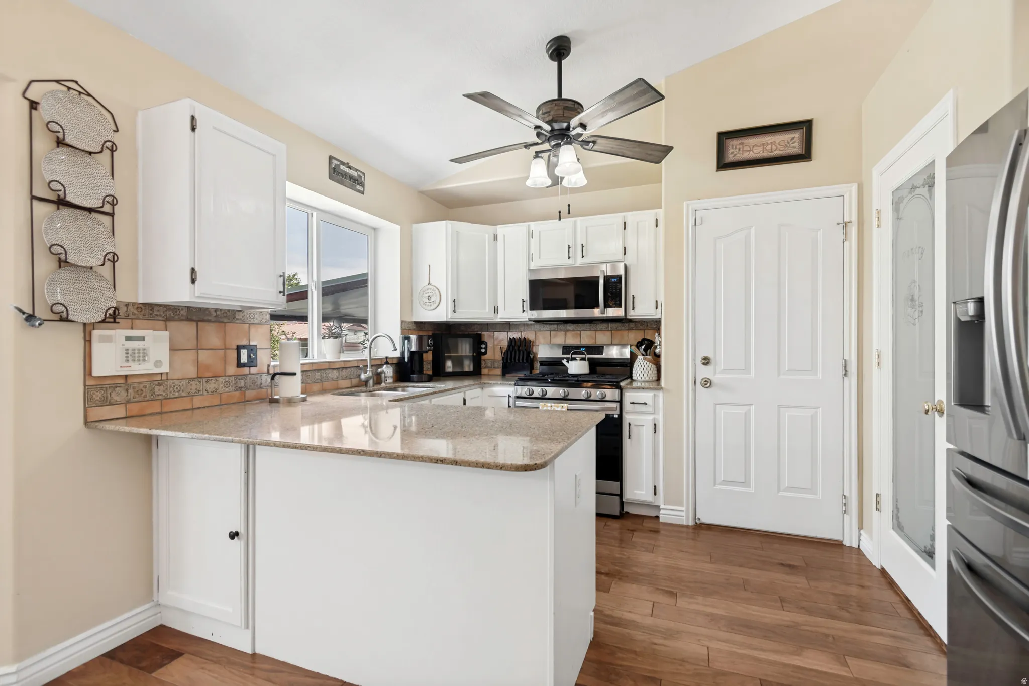 Kitchen featuring wood-finish flooring, white cabinetry, and granite-look countertops