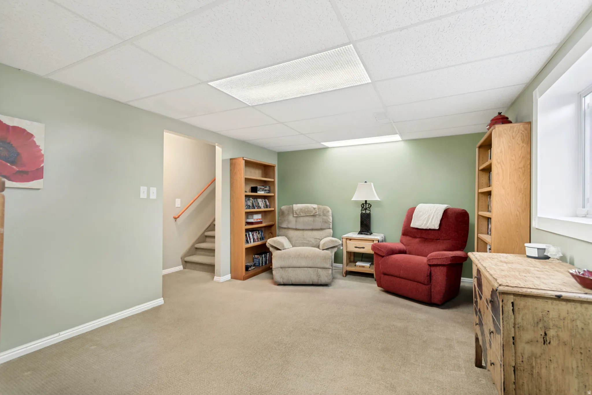 Carpeted recreational area with a drop ceiling featuring recessed lighting