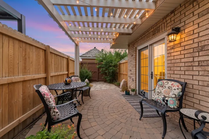 Patio area featuring a white pergola, string lighting, and an interlocking brick circular pattern
