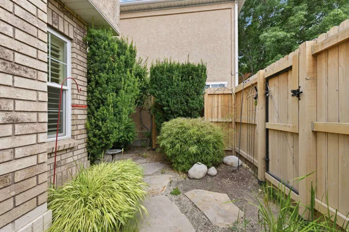 Side yard featuring a privacy fence with gate, mature evergreens, and flagstone pathway
