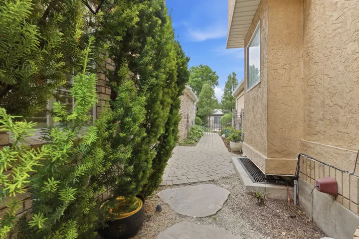 Stucco exterior with a paver pathway and mature landscaping