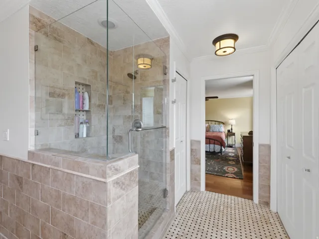 Glass-enclosed shower with subway tile surround, recessed shelving, and a built-in bench