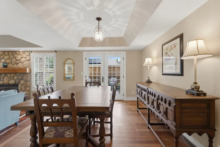 Spacious interior featuring wood-finish flooring, a tray ceiling with a central chandelier, and light-toned walls