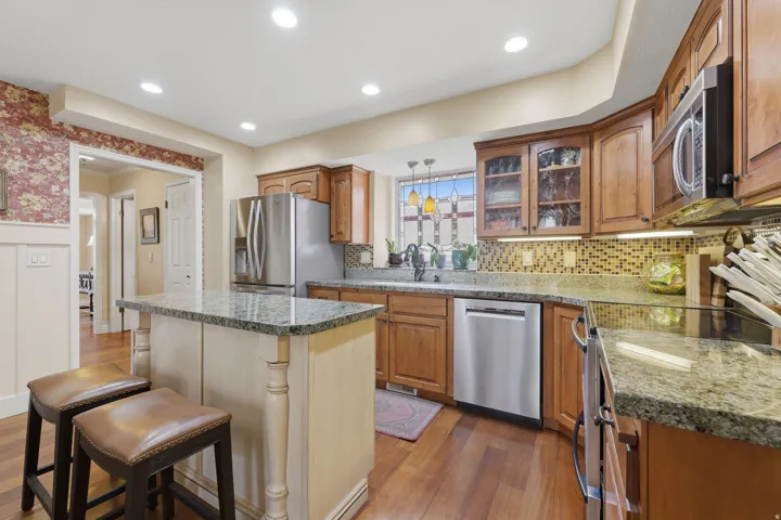 Well-appointed kitchen featuring wood-finish flooring, recessed lighting, and a central island with a stone countertop