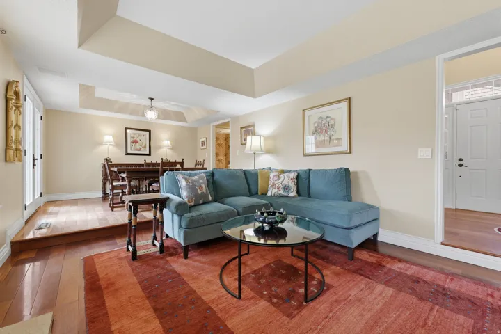 Open-concept living space featuring wood-finish flooring, a tray ceiling, and neutral-toned walls