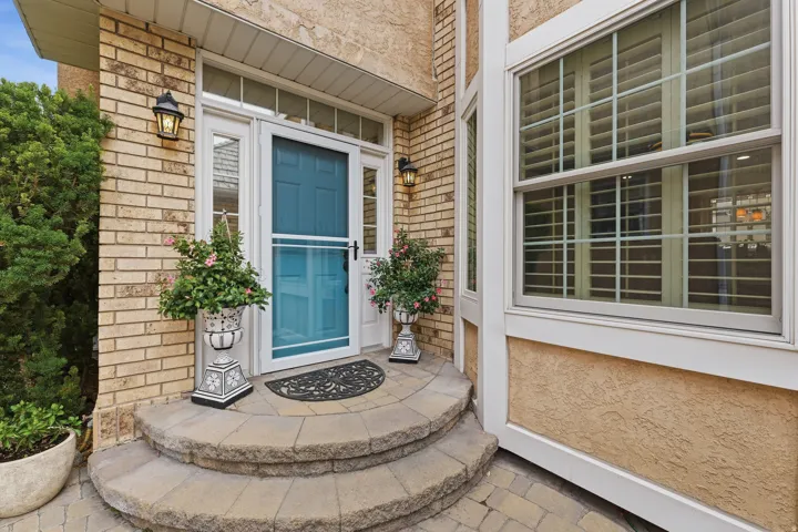 Brick and stucco exterior featuring a curved paver stone entryway
