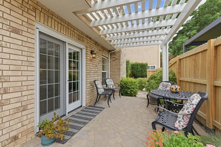 Covered patio featuring a white pergola, brick exterior, and a paver stone patio