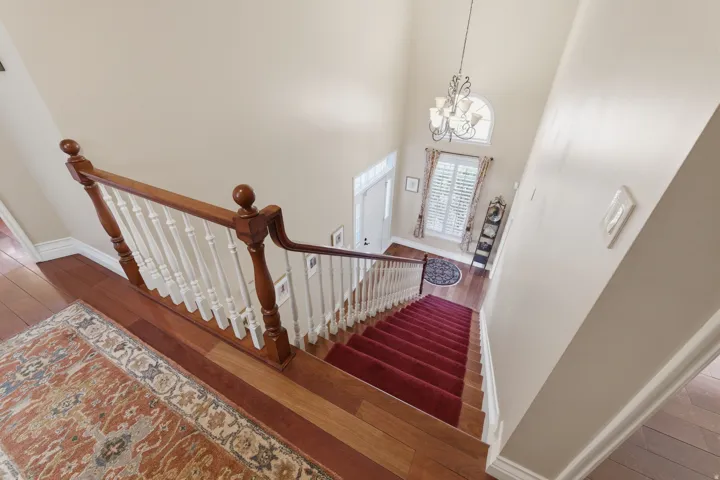 Hardwood flooring with a red carpeted staircase