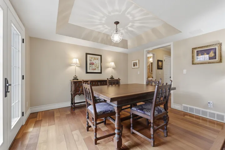 Tray ceiling with a decorative chandelier, wood-finish flooring, and white baseboards