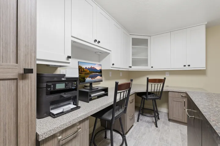 Dedicated office space featuring extensive built-in cabinetry, durable countertops, and a wood-finish door