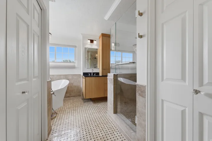 Bathroom featuring a freestanding tub, glass-enclosed shower, wood-finish vanity with dark countertop, and tiled floors