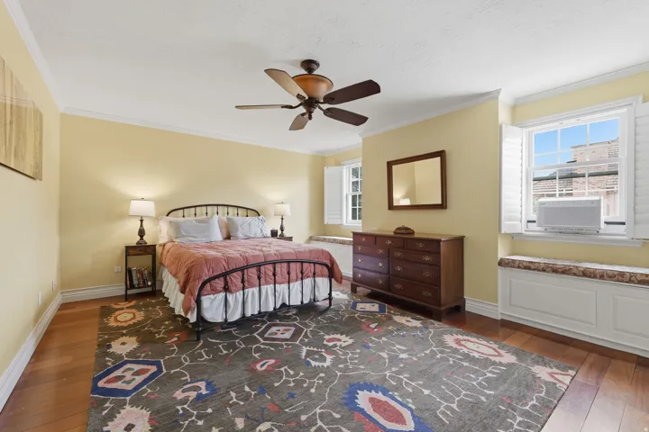 Spacious room featuring wood-finish flooring, a ceiling fan, and white crown molding