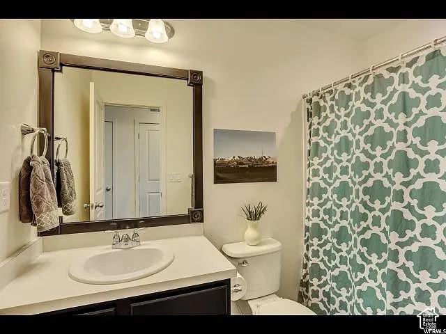 Bathroom featuring a single vanity with an oval undermount sink, a dark framed mirror, and a three-light vanity fixture