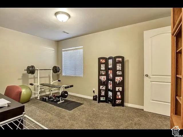 Carpeted room featuring a single window with horizontal blinds, a ceiling-mounted flush light fixture, and a solid interior door with an arched panel design