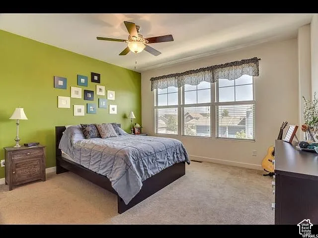 Spacious room featuring a multi-pane window, ceiling fan with integrated lighting, recessed baseboards, and neutral carpet flooring